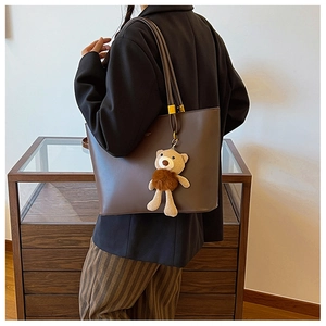 Detail view of deep brown large tote bag with teddy bear charm and gold buckles