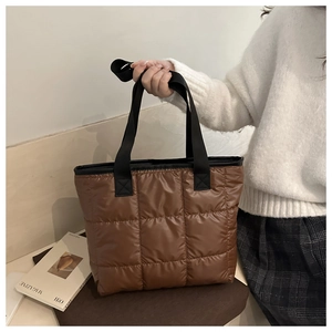 Close-up of brown quilted tote bag showing puffy nylon fabric and large grid patterns