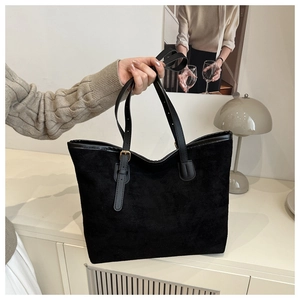Close-up of matte black suede tote bag with adjustable leather straps and metal buckle
