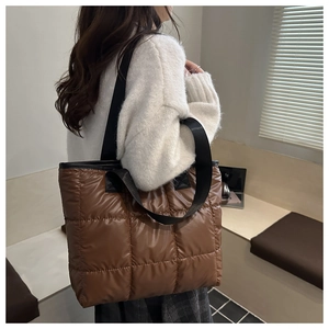 Brown quilted tote bag detail featuring high-gloss fabric and wide black woven straps