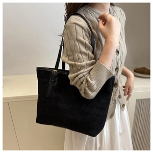Detail of minimalist black suede tote bag showing slim leather strap and gold metal buckle
