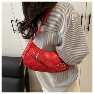 Detail of red crescent shoulder bag with metallic buckle straps and Y2K aesthetic design