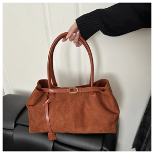 Close-up of brown suede tote bag with leather straps and elegant gold metal buckle detail