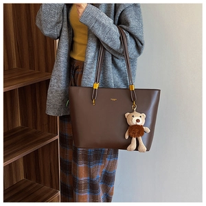 Detail of dark brown faux leather tote bag with gold hardware and bear charm accent