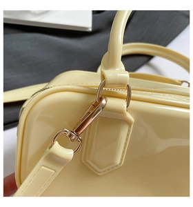 Macro shot of glossy cream yellow leather bag with gold metal buckle and fine stitching