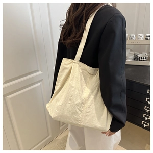 Detail of the pleated texture and silicone fashion label on this large beige tote bag
