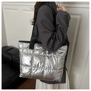 Detail of silver quilted tote bag with metallic finish and black nylon shoulder strap
