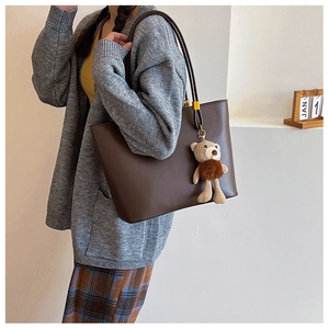 Detail view of large dark brown PU leather tote bag with a cute teddy bear charm