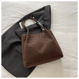 Detail der Leopard-Tasche mit geflochtenen Griffen und Seidenschal auf grauem Anzug