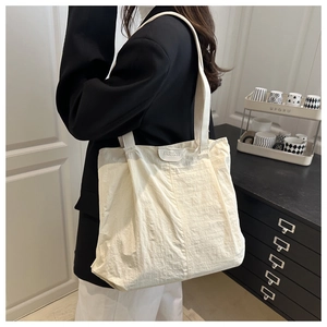 Detail of the ivory nylon tote bag featuring a Fashion label and large capacity interior