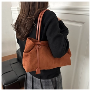 Detail of a large brown suede tote bag with long shoulder straps for office commute