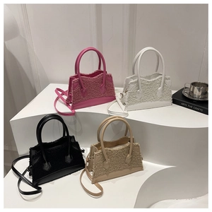 Detail view of colorful faux fur and leather patchwork handbags in pink, white, and black