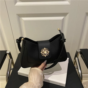 Sac sous le bras minimaliste en cuir noir avec boucle fleurie dorée sur livre