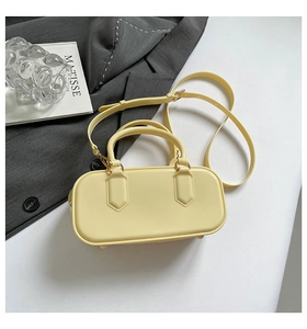 Detail of cream yellow leather handbag with gold hardware on a stylish suit background