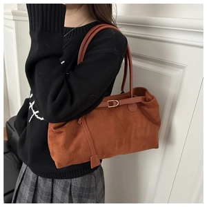 Détail d'un grand sac cabas marron en daim avec une fine bandoulière porté par un mannequin