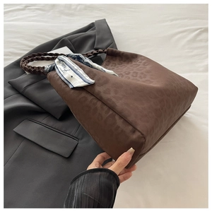 Nahaufnahme der braunen Leoparden-Tasche mit geflochtenen Griffen und Zierschal-Detail