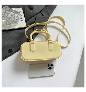 Close-up of a cream yellow jelly handbag with shiny finish shown with a mobile phone
