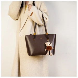 Detail of dark brown faux leather tote bag with gold hardware and bear charm on shoulder
