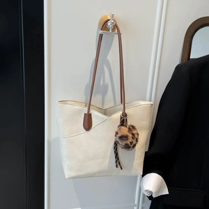 Minimalist off-white pebbled leather tote bag with brown straps and leopard pompom