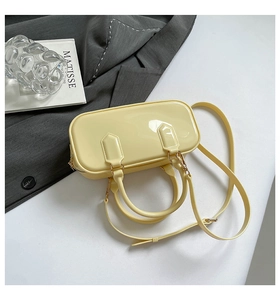 Flat lay of a glossy light yellow leather handbag with gold buckles and adjustable strap