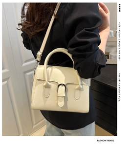 Detail of cream-colored vintage crossbody bag with silver buckle worn by a model