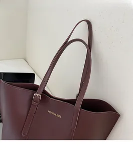 Detail of adjustable strap buckle and gold embossed logo on dark brown leather tote bag