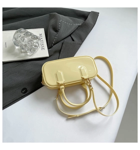 Top-down view of a glossy light yellow patent leather handbag with gold metal zippers