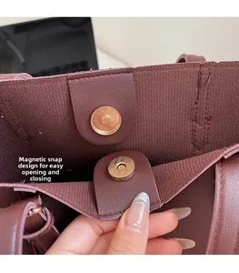 Detailed close-up of the magnetic buckle closure on a dark burgundy leather tote bag