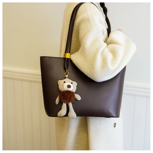 Detail of dark brown tote bag featuring unique corded straps and cute bear charm pendant