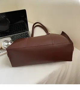 Detail of reinforced stitching and solid base of a large brown leather tote bag