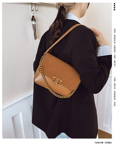 Model wearing a brown patchwork suede and leather shoulder bag with gold chain details