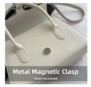 Detailed macro view of the metal magnetic buckle on this off-white crossbody bag