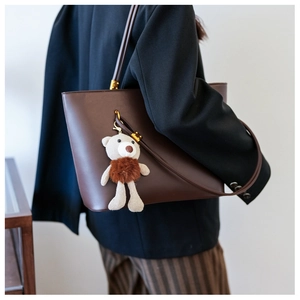 Detail of vintage brown PU leather tote bag with a cute knit bear pendant accessory