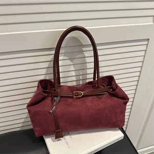 Retro burgundy suede tote bag with leather strap and gold buckle on a white surface