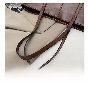 Detail of the rounded dark brown handle and fine stitching on the vintage tote bag