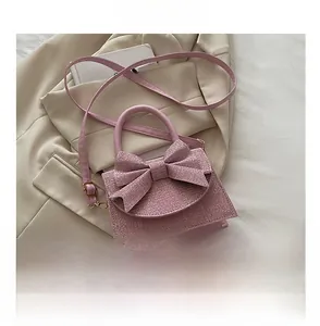 Detailed view of pink bow evening bag with sequin texture next to a smartphone for size