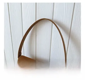 Detail of brown suede shoulder bag handle with elegant gold chain link decoration