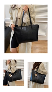 Detail view of large black oil wax leather tote bag with baseball pendant and long handles