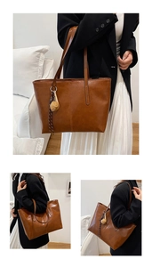 Detailed view of the brown oil-wax leather texture and vertical stitching on the tote bag