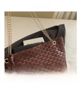 Macro view of brown fabric tote bag featuring full letter print and gold chain strap