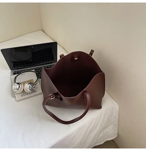 Gros plan d'un sac cabas en cuir mat marron avec lettrage doré près d'un ordinateur