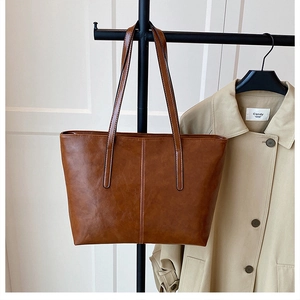 Close-up of brown PU leather tote bag with vertical stitching and thin shoulder straps