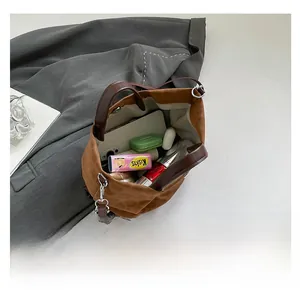 Interior storage view of brown suede bucket bag with daily essentials and leather handle
