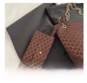 Detail of dark brown monogram tote bag with gold chain and matching mini pouch accessory