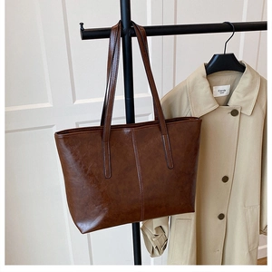 Dark brown retro tote bag hanging on a rack next to a beige trench coat for daily casual style