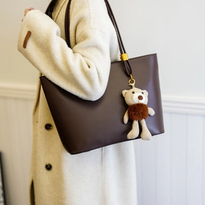 Large dark brown leather tote bag with gold hardware and a cute knit bear pendant