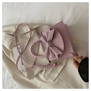 Detail der rosa Glitzertasche mit 3D-Schleife auf einem beigefarbenen Blazer