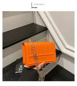 Detail of orange mini crossbody bag with vertical stitching and golden chain strap