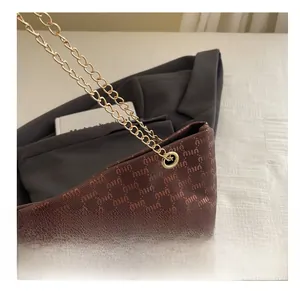 Close-up of brown jacquard tote with gold eyelet details and metallic chain strap