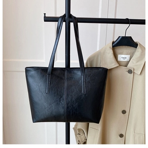 Detail of black large capacity tote bag with wrinkled texture hanging on a hanger